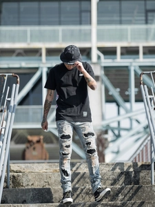 Street style view of men's slim ripped jeans with black sequin patches and black t-shirt