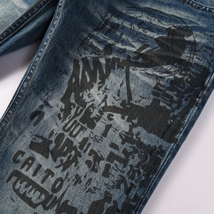 Close-up of black screen-printed Addict text on washed blue flared denim jeans for men
