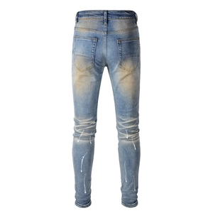 Detail of slim fit denim jeans featuring vintage wash and white paint splatter design
