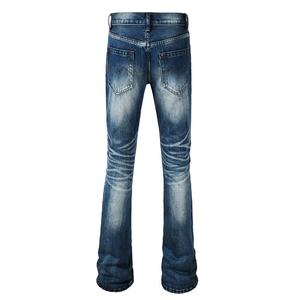 Detailed back view of flared blue jeans with orange M-shaped embroidery on back pockets