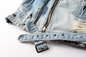 Detail of vintage blue denim jacket with distressed belt and metal hardware accents