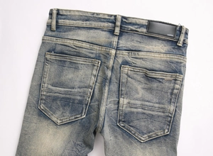 Détail d'un jean bleu avec écusson en cuir IXMIRI et texture de lavage intense