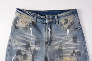Detail of light blue distressed jeans with white paint streaks and black ink splashes