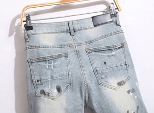 Close-up of denim jeans back pocket with black leather label and paint splatter detail