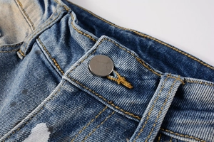 Macro shot of denim waist with metal button and artistic splatter ink detailing