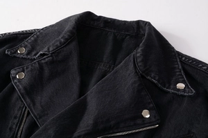 Detailed close-up of charcoal black denim jacket collar with silver buttons and wash texture