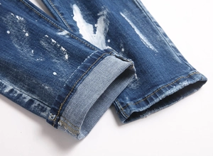 Detail of blue skinny jeans featuring distressed ripped holes and white paint splatter design