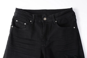 Detailansicht der schwarzen Jeans-Taille mit Silberknopf, Nieten und Distressed-Textur