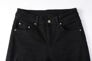 Detail of black distressed denim waist with silver metal button and reinforced rivets