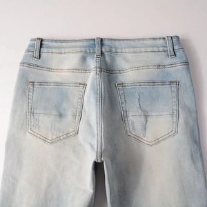 Detail view of light blue distressed jeans showing back pockets and faded denim texture