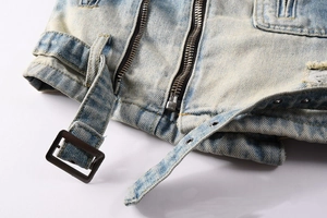 Detail of distressed denim jacket with vintage wash, dual metal zippers and waist belt