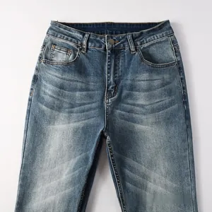 Détail du denim délavé bleu avec bouton métallique et texture effet moustaches