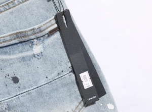Close-up of blue distressed denim with paint splatters and branding labels