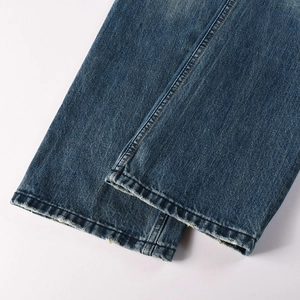 Detailed close-up of double-stitched hem and faded blue denim texture on men's flare jeans