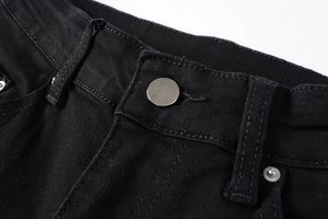 Detailed close-up of the black denim waist with silver metal button and stitching