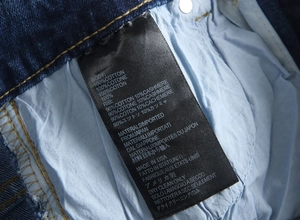 Detail of care label showing 100% cotton material and made in USA origin on denim pants