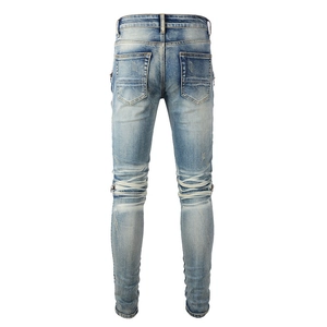 Detail view of light blue biker jeans with knee pleats and washed denim texture