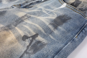 Macro detail of distressed denim jeans featuring vintage floral tie-dye print and stitching