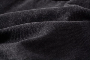 Macro detail of charcoal grey heavy denim fabric with twill texture and washed finish