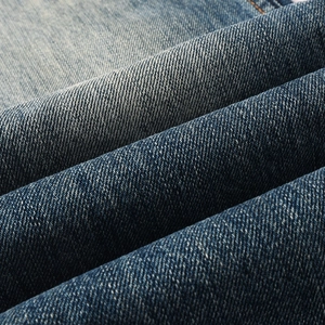 Close-up of deep blue denim fabric texture with washed finish on men's flare jeans