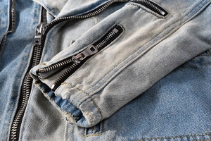 Macro detail of heavy-duty washed denim jacket with metal zipper on the sleeve cuff
