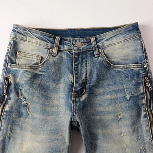 Detail of vintage blue distressed jeans featuring metal zipper and rusted wash effect