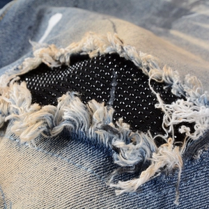 Slim fit light blue distressed denim jeans with black rhinestone patchwork detail
