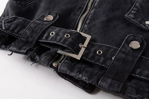 Detailed close-up of vintage black denim jacket waist with silver buckle and distressed edge