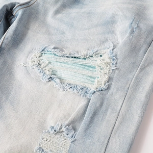 Detailed close-up of light blue distressed jeans showing patches and ripped denim texture