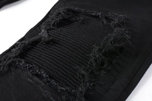 Detail von schwarzer Jeans mit Rissen, destroyed Patches und Falten im Biker-Stil