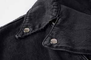 Close-up of distressed black denim jacket featuring silver metal snaps and zipper detail
