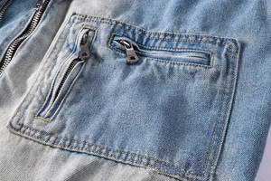 Detail of light blue washed denim jacket featuring double metal zippers and contrast stitching
