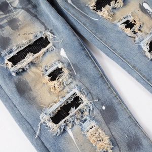 Distressed blue slim fit jeans with vintage wash, ripped patches and white ink splash paint