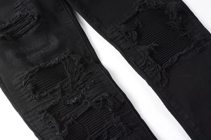 Detailansicht der schwarzen Moto-Jeans mit geripptem Patchwork und ausgefransten Kanten