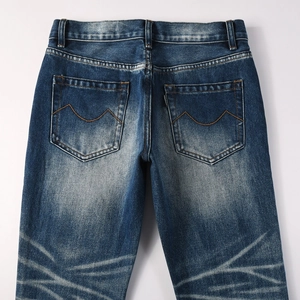 Flat lay of blue flared jeans showing back pockets with orange M stitching and washed finish