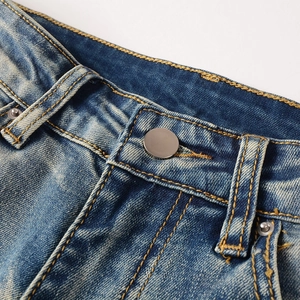 Detail view of washed denim waist with yellow stitching and metallic button