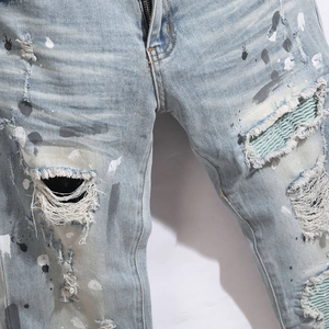 Men's light blue distressed skinny jeans with paint splatters and denim patches