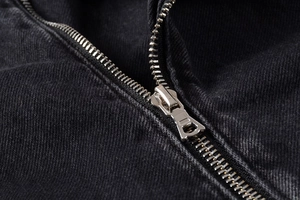 Macro shot of high-quality metal zipper detail on black denim motorcycle jacket
