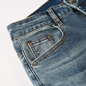Détail de la taille d'un jean bleu avec bouton métallique et texture délavée