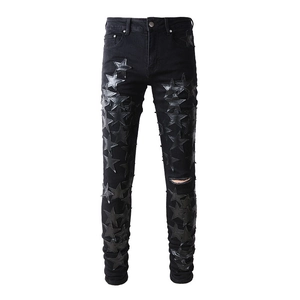 Slim fit black denim jeans with leather star patches and distressed knee details for men