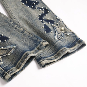 Jean bleu clair ajusté avec broderie étoile et perles sur l'ourlet de jambe effiloché
