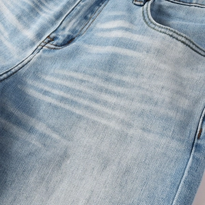 Detailed close-up of light blue flared jeans showing whisker wash and denim texture