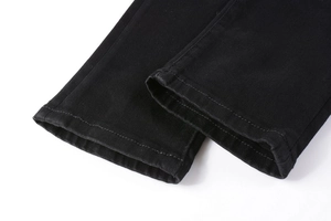 Nahaufnahme von schwarzen Jeans-Beinabschlüssen mit Köperstoff-Struktur und präziser Nahtführung