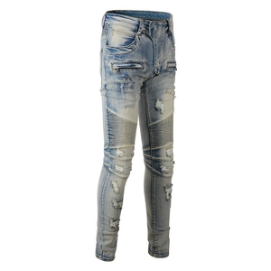 Detail of distressed biker jeans showing knee pleats and ripped light blue wash denim