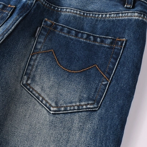 Detailed macro view of dark blue washed denim rear pocket with decorative stitching