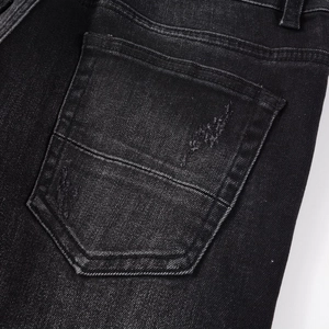 Close-up of distressed back pocket on black washed slim fit denim jeans for men
