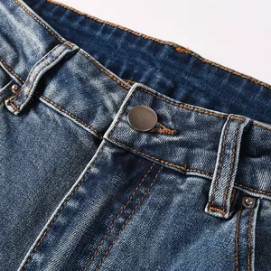 Vue macro de la ceinture en denim bleu avec bouton en métal et surpiqûres orange