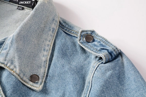 Macro shot of blue denim jacket collar with epaulettes and circular metal buttons