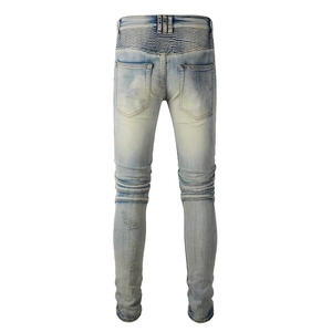 Macro detail of biker-style accordion pleats and distressed wash on men's slim denim jeans