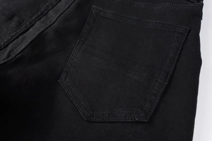 Detail of high-street black distressed jeans showing back pocket stitching and twill fabric